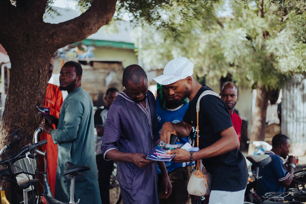 About Men engaging in conversation under a tree in a vibrant urban community.